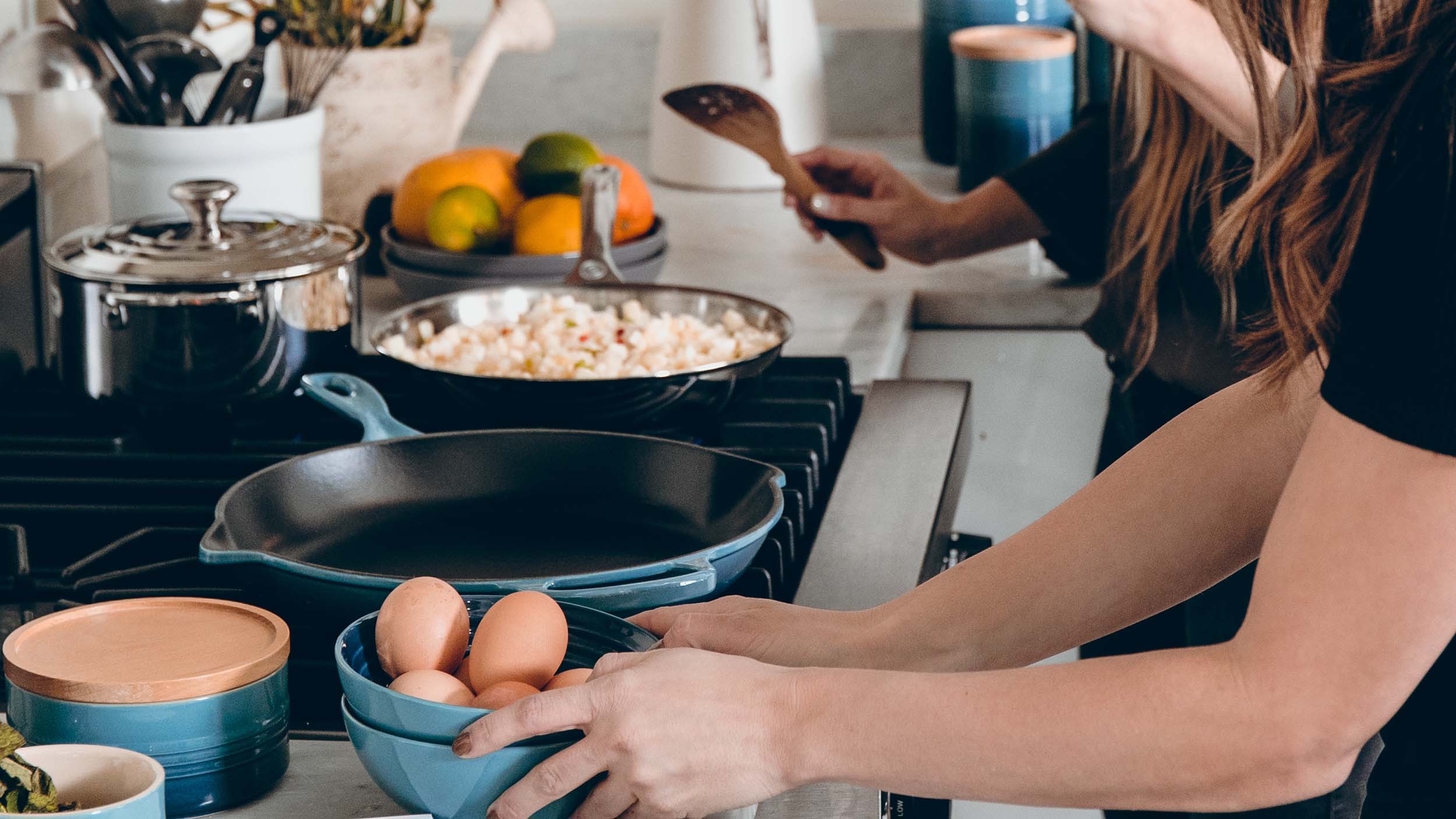 Two women cooking on a gas stove
